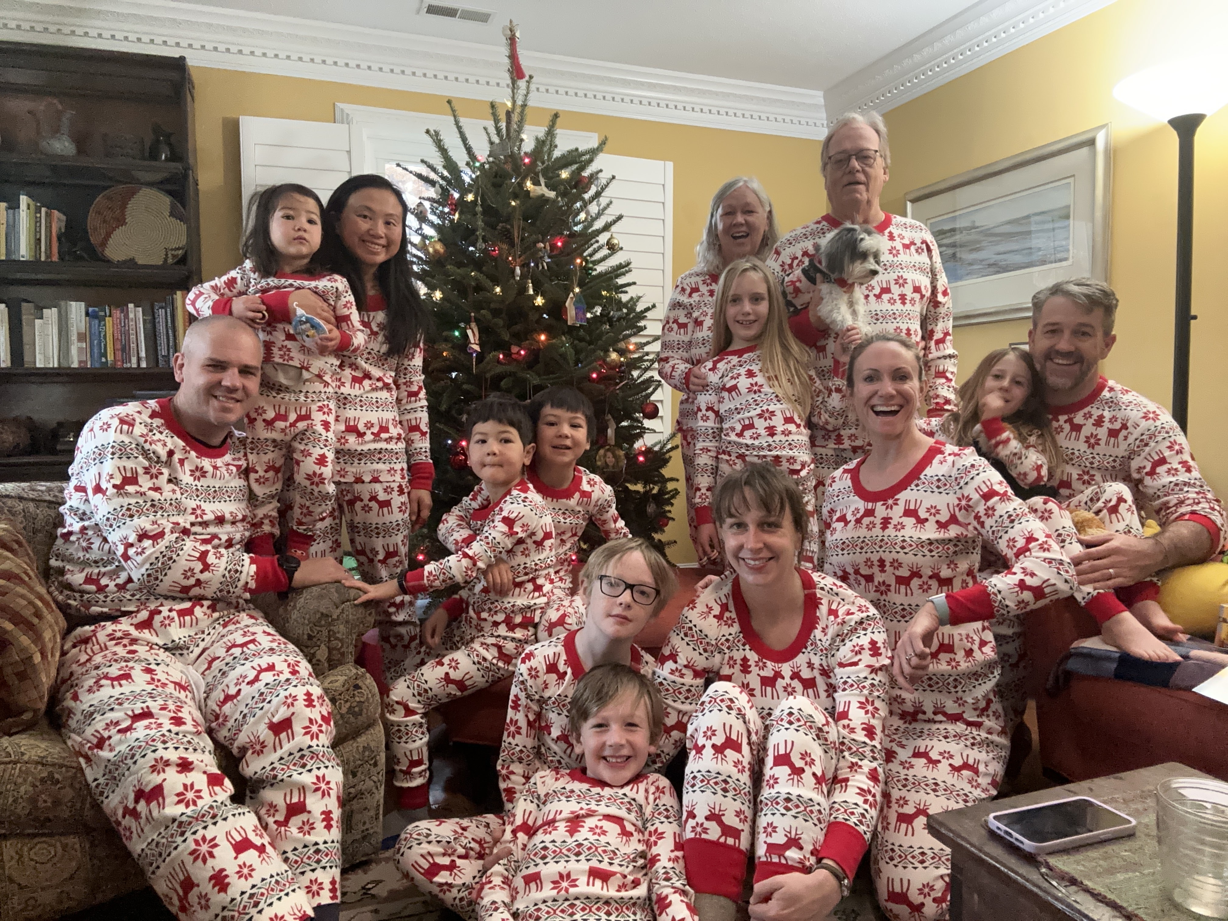 The whole family in matching holiday pajamas around the Christmas tree